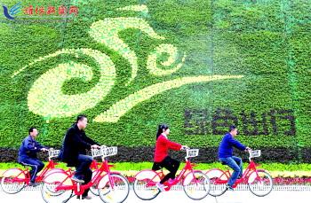 市民騎公共自行車路過市人民廣場一處花壇。記者 張馳